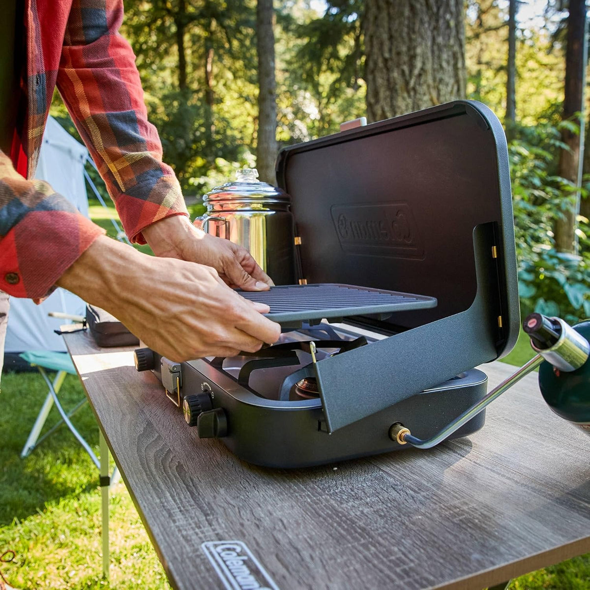 The 1900 series three-in-one propane camping stove, featuring a cast iron grill and frying pan accessories, has a power output of 24000 watts. It is equipped with an adjustable flame cover and excellent lighting device, and comes with two adjustable